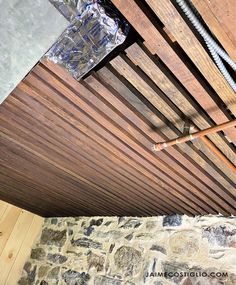 the inside of a house with wood slats and metal pipes attached to it's ceiling