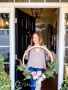 a woman holding a wreath in front of a door