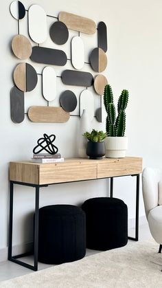 a wooden table topped with a potted plant next to a wall mounted art piece