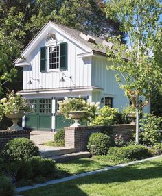 a white house with green shutters in the front yard and trees on either side