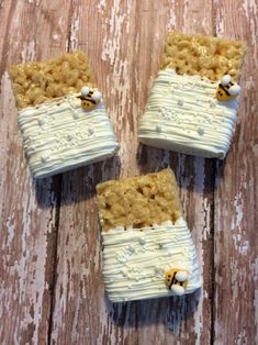 three pieces of food that are on top of a wooden table with white frosting