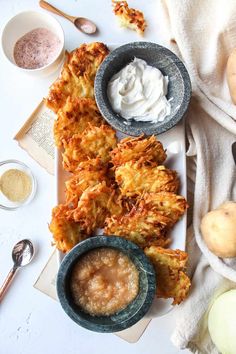 some food is sitting on a white plate and next to bowls with dipping sauces