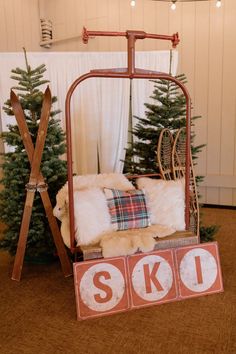 an old fashioned swing bed with pillows and skis on the floor next to a christmas tree