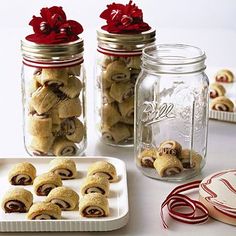 some cookies are sitting on a plate next to two glass jars with red bows and candy canes