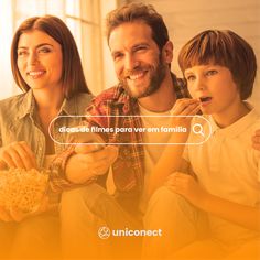 a man and two children sitting on the floor eating popcorn while looking at something in front of them