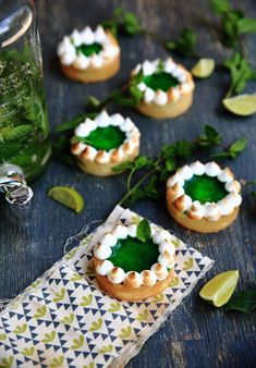 small desserts with green leaves and white frosting on them sitting on a table