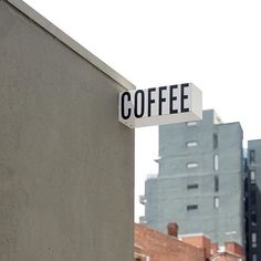 a street sign that reads coffee on the side of a building with buildings in the background