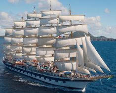 a large white sail boat sailing in the ocean with lots of people on it's side