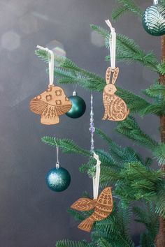 three wooden ornaments hanging from a tree with green and blue ornaments on it's branches