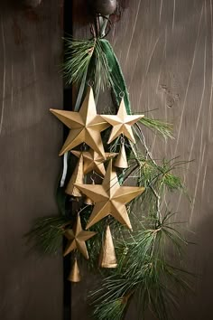 an origami star hanging from a door with pine needles and bells attached to it