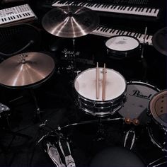 a drum set with two sticks in front of it and several keyboards on the side