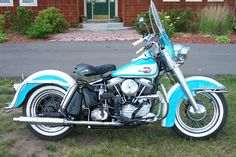 a blue and white motorcycle parked in front of a house