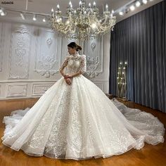 a woman in a white wedding dress standing on a wooden floor next to a chandelier