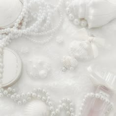 some white items are laying out on a tablecloth with pearls and seashells