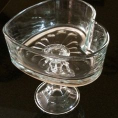 an empty glass bowl sitting on top of a black table with its reflection in it