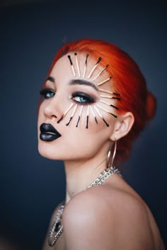 a woman with red hair and black makeup has her face painted like a starburst