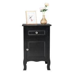 a small black cabinet with flowers and a picture frame on it's side table