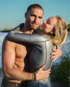 a man and woman embracing each other while standing next to a body suit on the beach