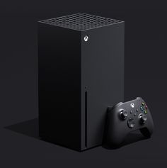 a black video game console next to a controller on a dark background with the xbox logo above it