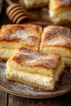 several pieces of cake on a plate with honey sticks in the backgroung