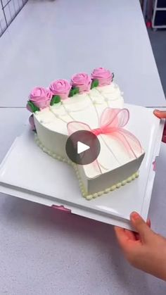 someone is cutting into a cake with pink roses on it and the video appears to be being viewed