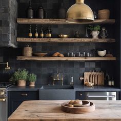 a kitchen with black walls and shelves filled with items on the counter top, along with a wooden cutting board