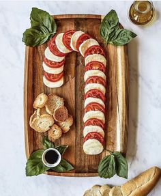 sliced tomatoes, mozzarella and basil on a wooden platter with garlic bread