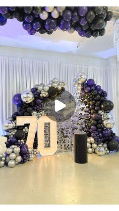 the balloon arch is decorated with black, white and silver balloons that spell out the number seventy