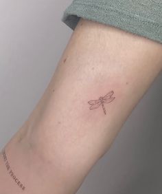 a small dragonfly tattoo on the arm