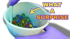 a person in purple gloves holding a bucket filled with marbles and the words what a surprise