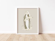 a white framed art print with an image of the virgin mary holding flowers in her hands