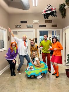 a group of people in costumes posing for a photo with a dog on a toy car