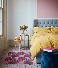 a bedroom with a bed, side table and colorful rug on the floor next to it