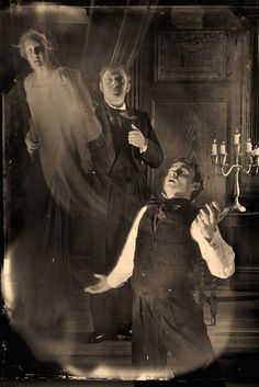 an old black and white photo of three men dressed up in victorian garb with candles on the table