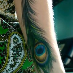 a woman with a peacock feather tattoo on her arm