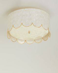 a white ceiling light with scalloped edges and a gold trim around the edge