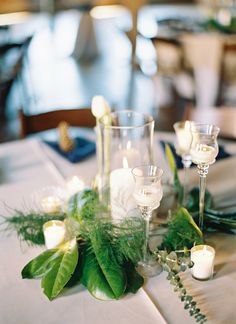 the table is set with candles and greenery