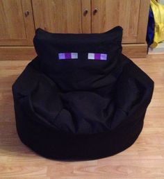 a black bean bag chair sitting on top of a hard wood floor next to cabinets