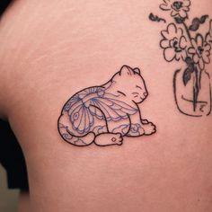 a small tattoo on the back of a woman's stomach with a cat and flower vase behind it