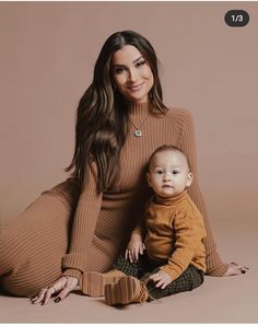 a woman sitting on the ground holding a baby