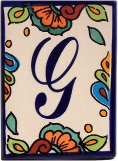 a ceramic tile with the letter g in blue, orange and green flowers on it