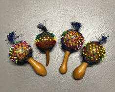 three wooden spoons with colorful beads and tassels on them sitting next to each other