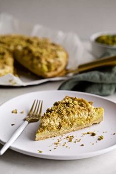 a piece of quiche on a plate with a fork next to the rest of the pie