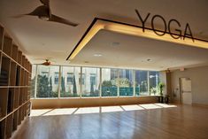 an empty room with large windows and a yoga sign on the wall that says yoga