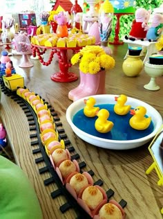 a toy train with yellow rubber ducks on the track next to flowers and other toys