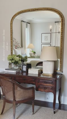 a desk with a mirror and lamp on top of it in front of a couch