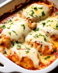 a casserole dish with meat and cheese covered in parmesan sauce, garnished with fresh herbs