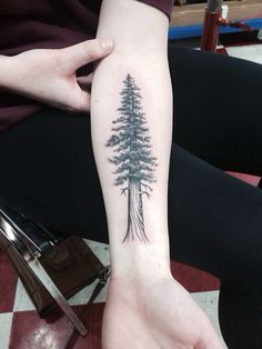 a woman's arm with a pine tree tattoo on it