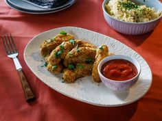 a white plate topped with fried chicken next to a bowl of sauce and a fork