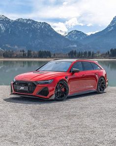 a red car parked in front of a lake